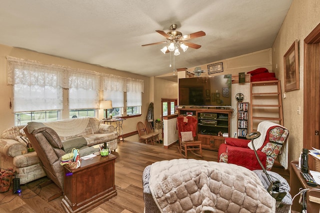 living area with a ceiling fan, vaulted ceiling, and wood finished floors