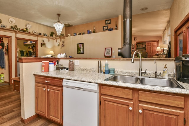 kitchen featuring white dishwasher, a sink, wood finished floors, light countertops, and brown cabinets