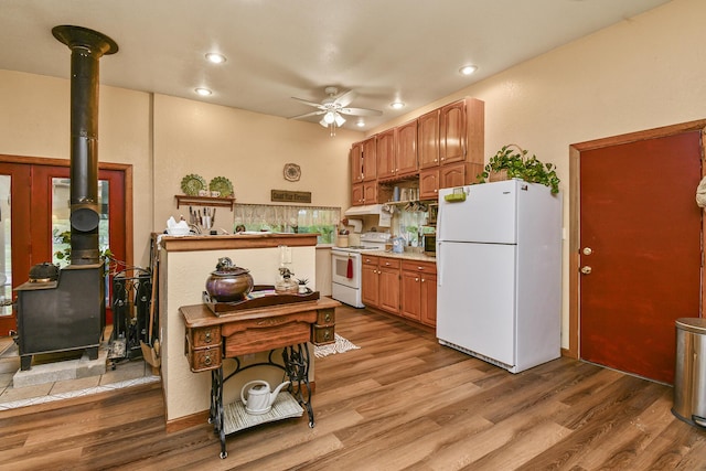 kitchen with white appliances, a wood stove, ceiling fan, wood finished floors, and recessed lighting