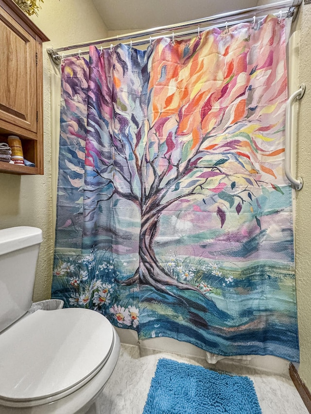 full bath featuring a textured wall, toilet, and curtained shower