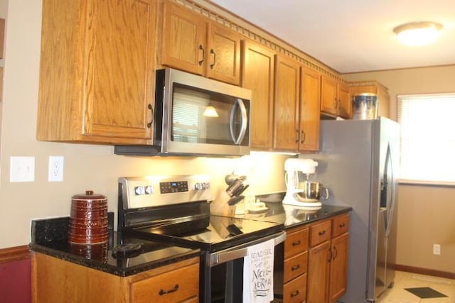 23197 Oakwood Cir, Hermitage, MO 65668 - kitchen with stainless steel appliances, brown cabinetry, dark stone countertops, and baseboards