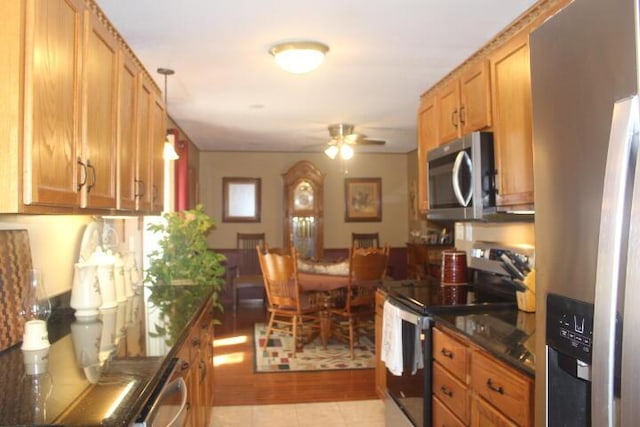 23197 Oakwood Cir, Hermitage, MO 65668 - kitchen with appliances with stainless steel finishes, dark countertops, a ceiling fan, light tile patterned flooring, and brown cabinets