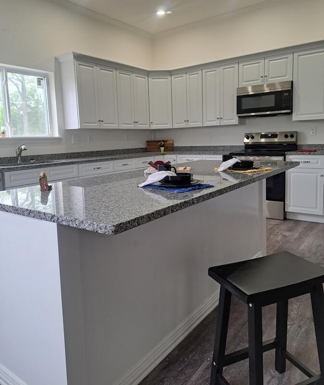 137 Vista Ln, Granby, MO 64844 - kitchen featuring stainless steel appliances, dark wood-type flooring, light stone countertops, a kitchen island, and a sink