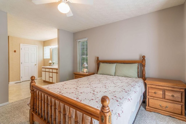 bedroom with light carpet, baseboards, ceiling fan, connected bathroom, and a textured ceiling