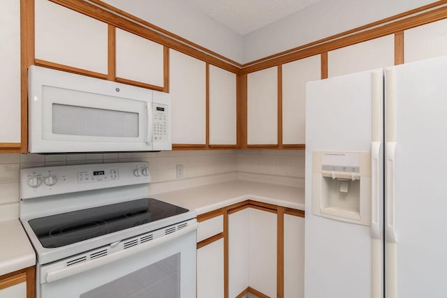 kitchen featuring white appliances, tasteful backsplash, light countertops, and white cabinetry