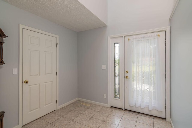 entryway with baseboards and light tile patterned floors