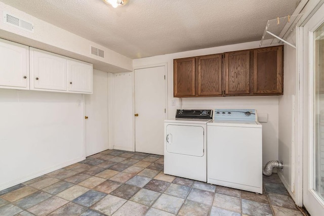 laundry room featuring cabinet space, stone finish floors, independent washer and dryer, a textured ceiling, and baseboards