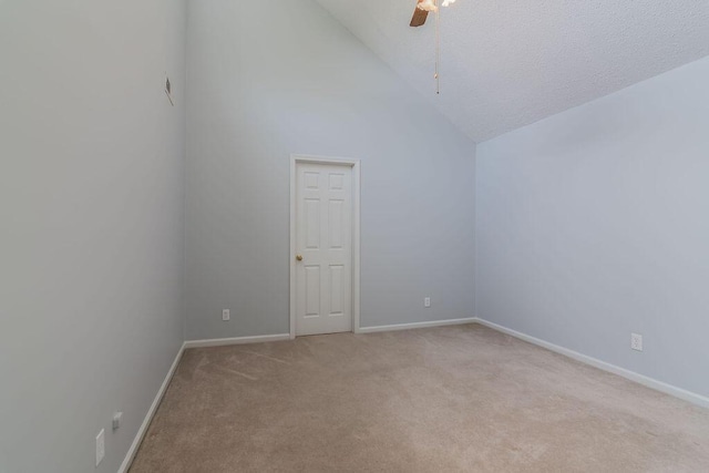 spare room with light carpet, vaulted ceiling, a ceiling fan, baseboards, and a textured ceiling