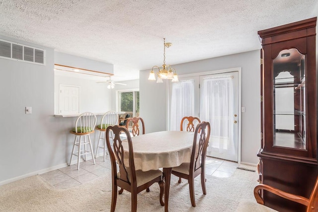 dining room featuring light colored carpet, a chandelier, baseboards, light tile patterned floors, and a ceiling fan