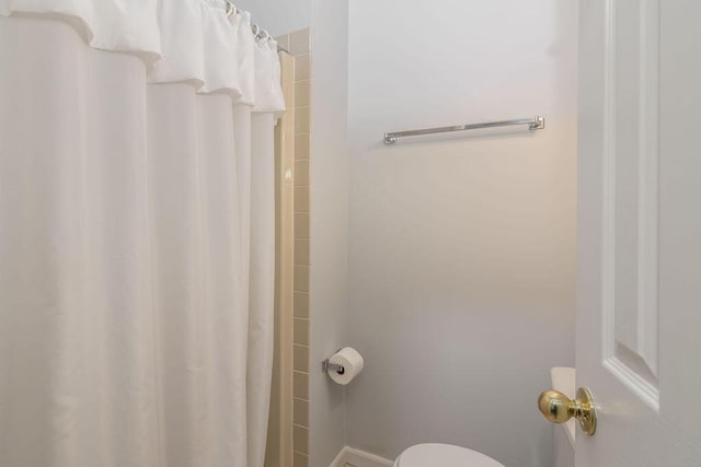 bathroom featuring curtained shower and toilet