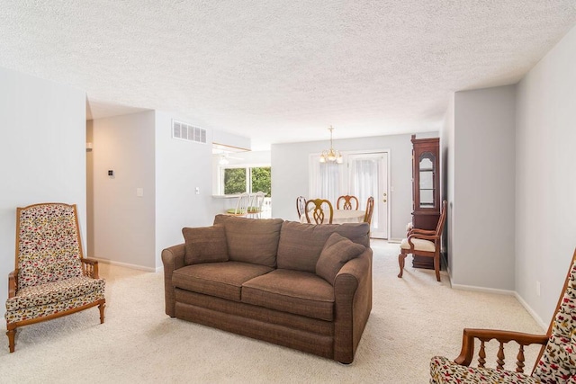 living room with light colored carpet, a chandelier, a textured ceiling, and baseboards