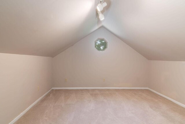 bonus room with light carpet, vaulted ceiling, and baseboards