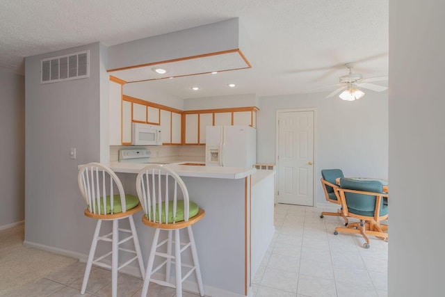 kitchen with white appliances, light countertops, ceiling fan, a breakfast bar, and light tile patterned flooring