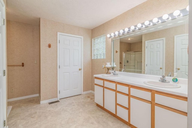 bathroom with a shower stall, double vanity, and baseboards