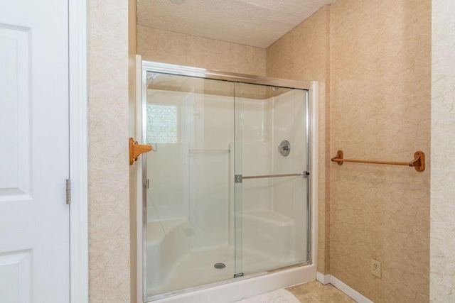 full bath with a shower stall and a textured ceiling