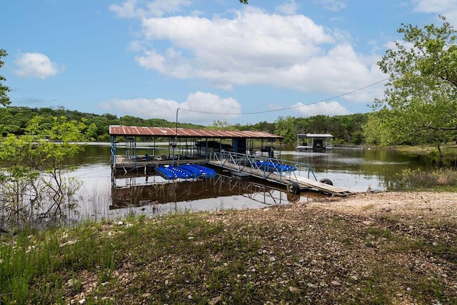 dock with a water view, boat lift, and a view of trees