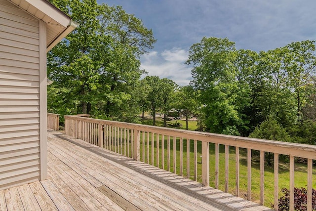wooden terrace with a lawn and view of wooded area