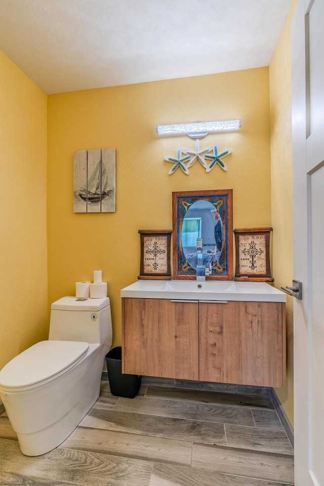 bathroom featuring toilet, wood finished floors, and vanity