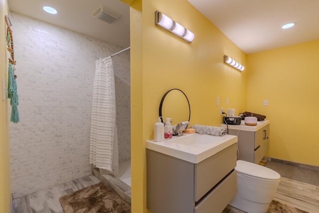 bathroom featuring vanity, a stall shower, recessed lighting, toilet, and wood finished floors
