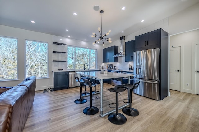 139 Cherokee Dr, Kimberling City, MO 65686 - kitchen with appliances with stainless steel finishes, wall chimney exhaust hood, light countertops, light wood-style floors, and backsplash