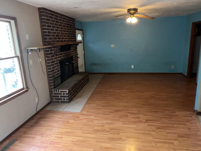 9556 N State Highway H, Pleasant Hope, MO 65725 - unfurnished living room with light wood-type flooring, a ceiling fan, a fireplace, and baseboards