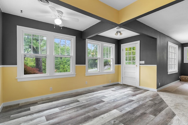unfurnished room with wood finished floors, a ceiling fan, plenty of natural light, and baseboards