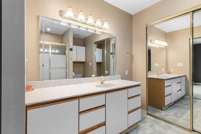 full bathroom with vanity, toilet, a stall shower, and a textured wall