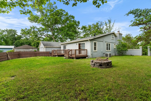 rear view of house with an outdoor fire pit, a wooden deck, central AC unit, a chimney, and stucco siding