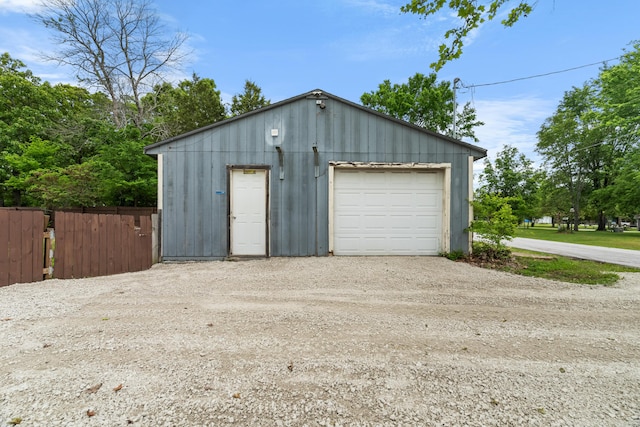 detached garage with dirt driveway and fence