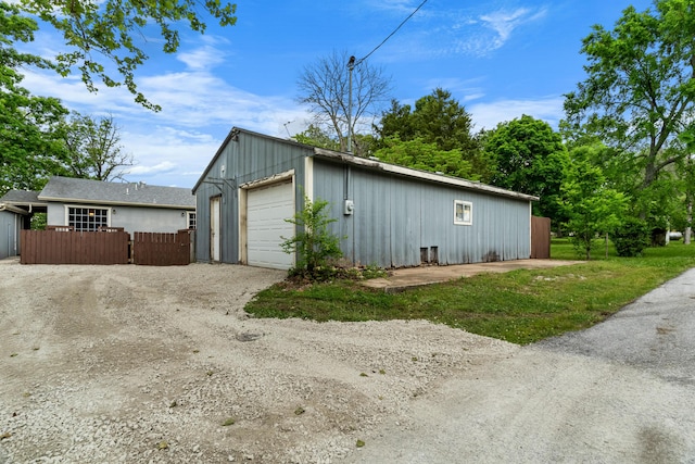 detached garage with fence and dirt driveway