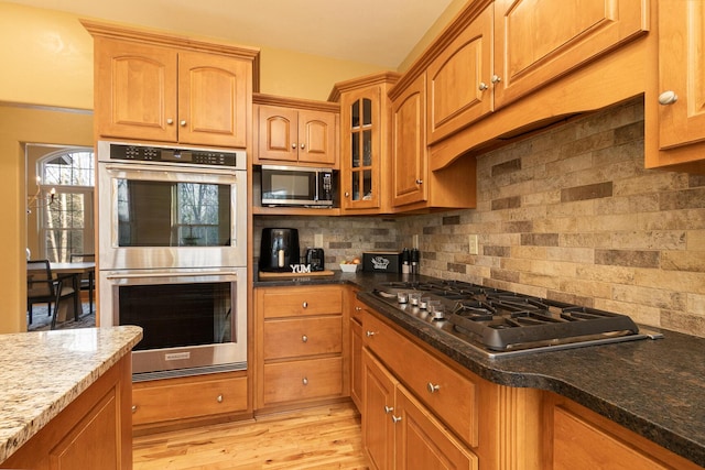 143 Woodfield Dr, Highlandville, MO 65669 - kitchen with stainless steel appliances, decorative backsplash, glass insert cabinets, light wood finished floors, and dark stone countertops