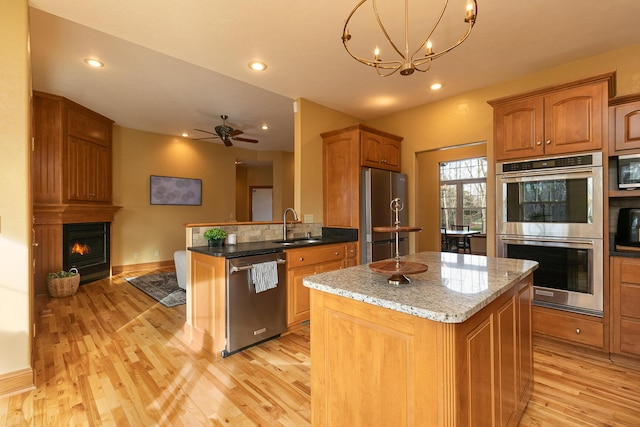 143 Woodfield Dr, Highlandville, MO 65669 - kitchen featuring stainless steel appliances, a sink, light wood-type flooring, a center island, and light stone countertops