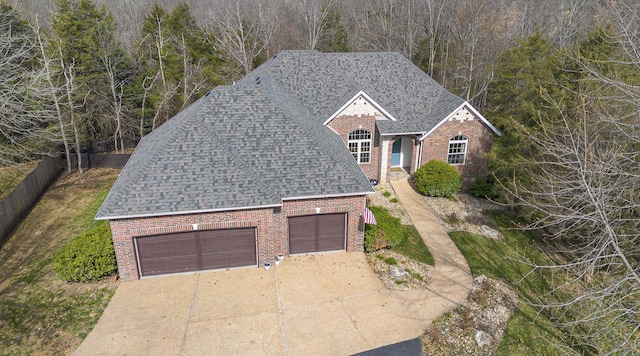 143 Woodfield Dr, Highlandville, MO 65669 - view of front facade with brick siding, an attached garage, concrete driveway, a shingled roof, and fence