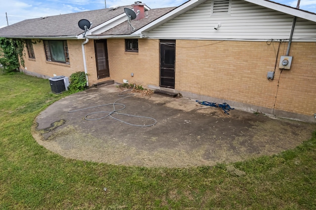 rear view of property featuring a patio, a yard, brick siding, and roof with shingles