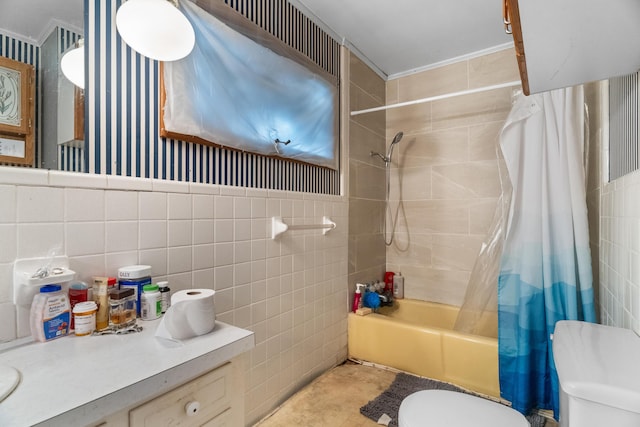 bathroom featuring toilet, tile walls, shower / bath combo with shower curtain, and vanity