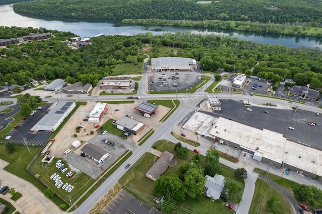 aerial view of property and surrounding area featuring a nearby body of water and a forest