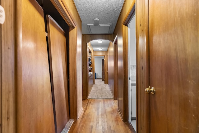 corridor featuring hardwood / wood-style flooring, a textured ceiling, and arched walkways