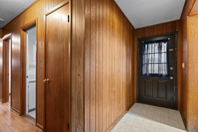 doorway featuring wood walls and a textured ceiling