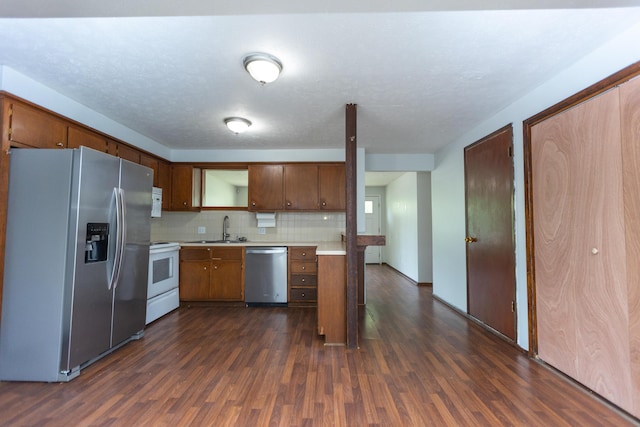 kitchen featuring stainless steel appliances, dark wood finished floors, light countertops, decorative backsplash, and a sink