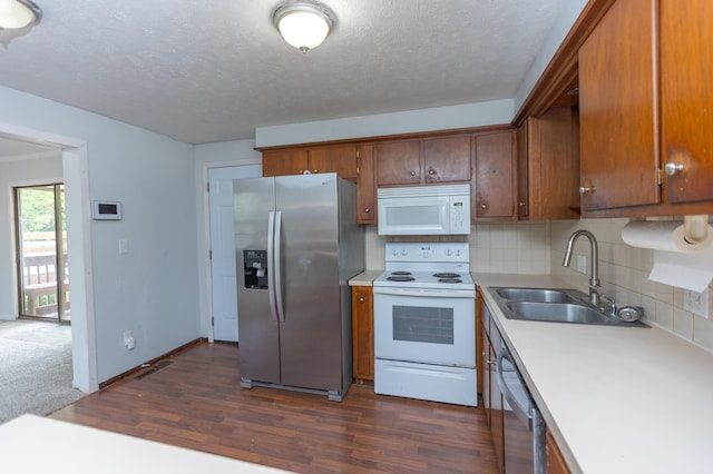 kitchen with appliances with stainless steel finishes, a sink, light countertops, dark wood-type flooring, and backsplash
