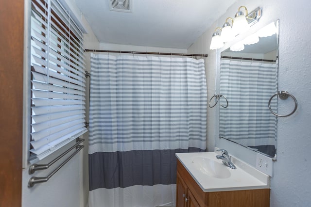bathroom featuring vanity, a textured wall, and a shower with curtain