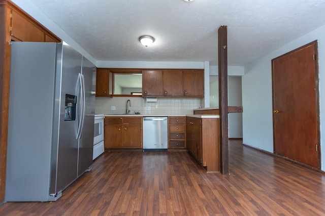 kitchen with stainless steel appliances, dark wood-type flooring, light countertops, tasteful backsplash, and a sink