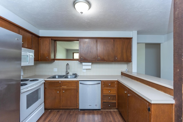 kitchen with appliances with stainless steel finishes, a sink, dark wood-style floors, light countertops, and a textured ceiling