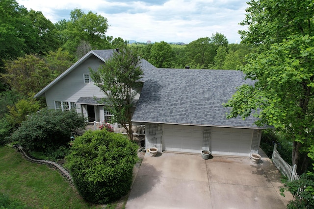 view of front of house with roof with shingles, driveway, an attached garage, and fence