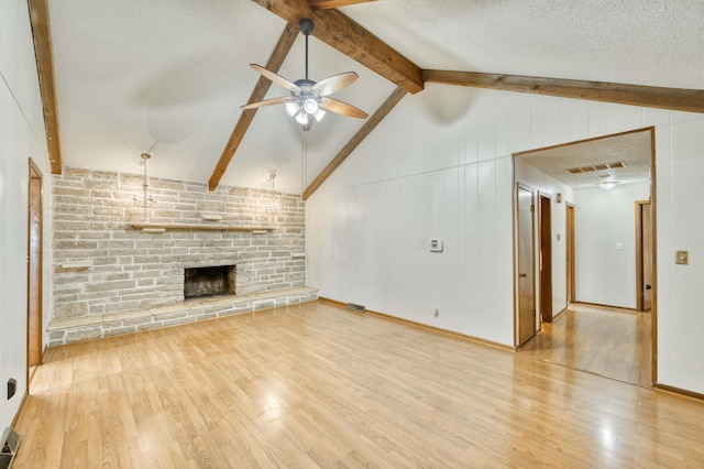 4852 S Charleston Ave, Springfield, MO 65804 - unfurnished living room with a ceiling fan, wood finished floors, a stone fireplace, and a textured ceiling