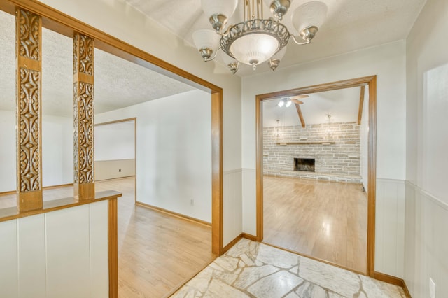 4852 S Charleston Ave, Springfield, MO 65804 - unfurnished dining area with light wood finished floors, a brick fireplace, a wainscoted wall, a chandelier, and a ceiling fan