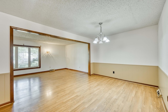 4852 S Charleston Ave, Springfield, MO 65804 - unfurnished room with a chandelier, a textured ceiling, light wood-style floors, and wainscoting