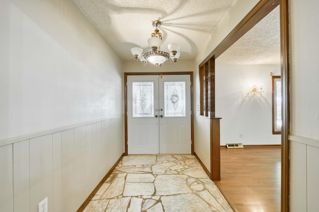 4852 S Charleston Ave, Springfield, MO 65804 - foyer featuring a textured ceiling, a chandelier, light wood-style flooring, plenty of natural light, and french doors