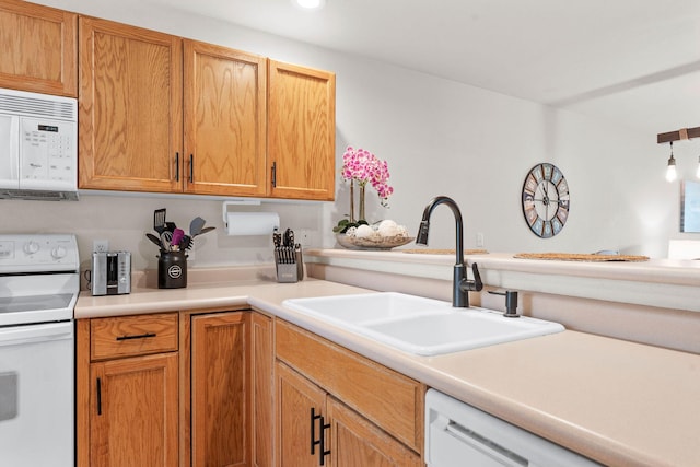 kitchen featuring white appliances, a sink, light countertops, and recessed lighting