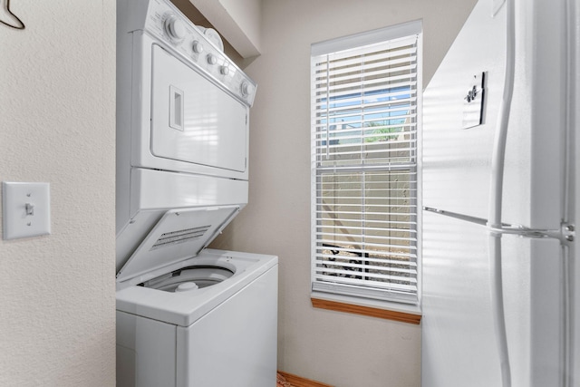 laundry room featuring stacked washer / dryer and a textured wall